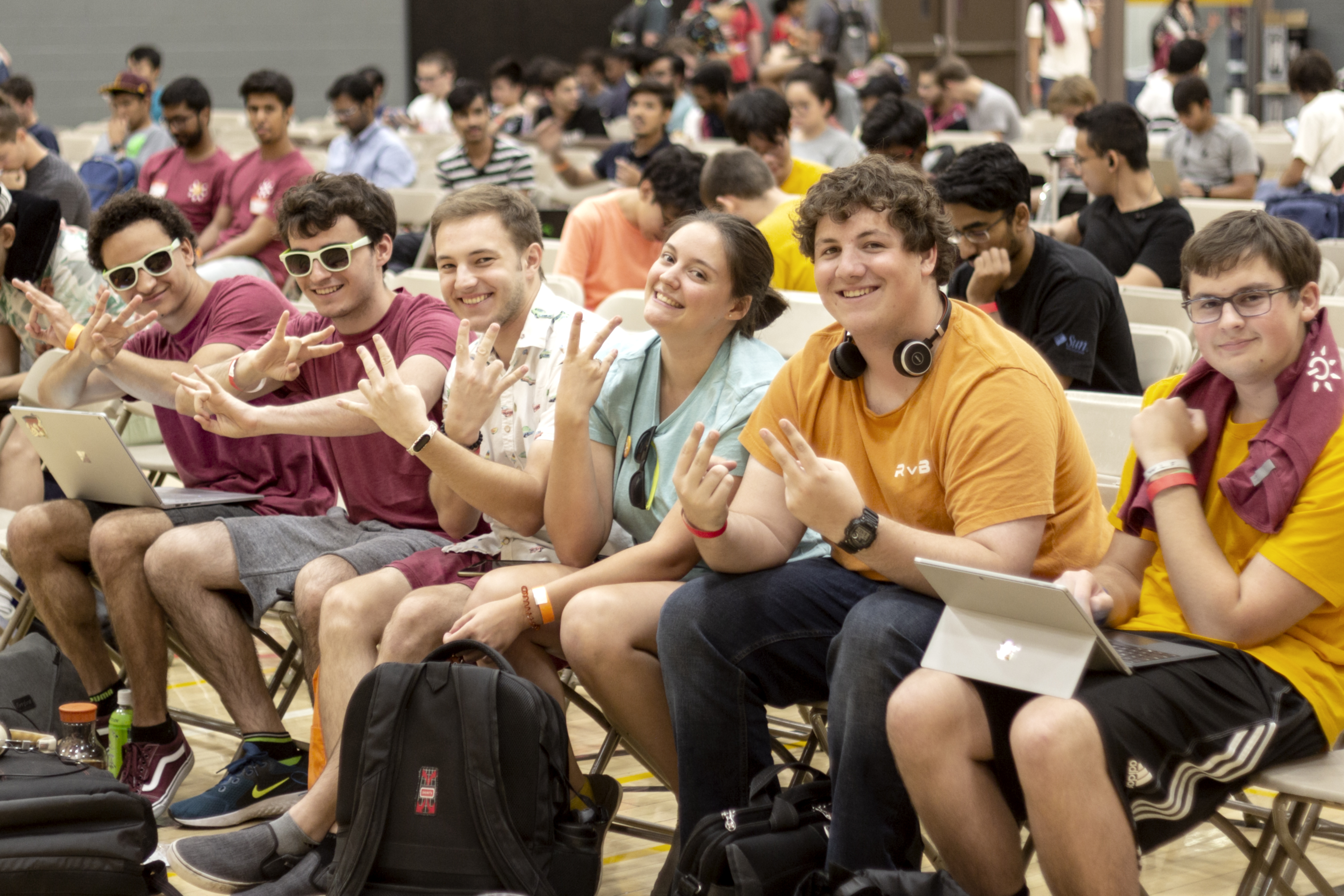 A group of students holding up pickfork gestures at sunhacks opening ceremonies